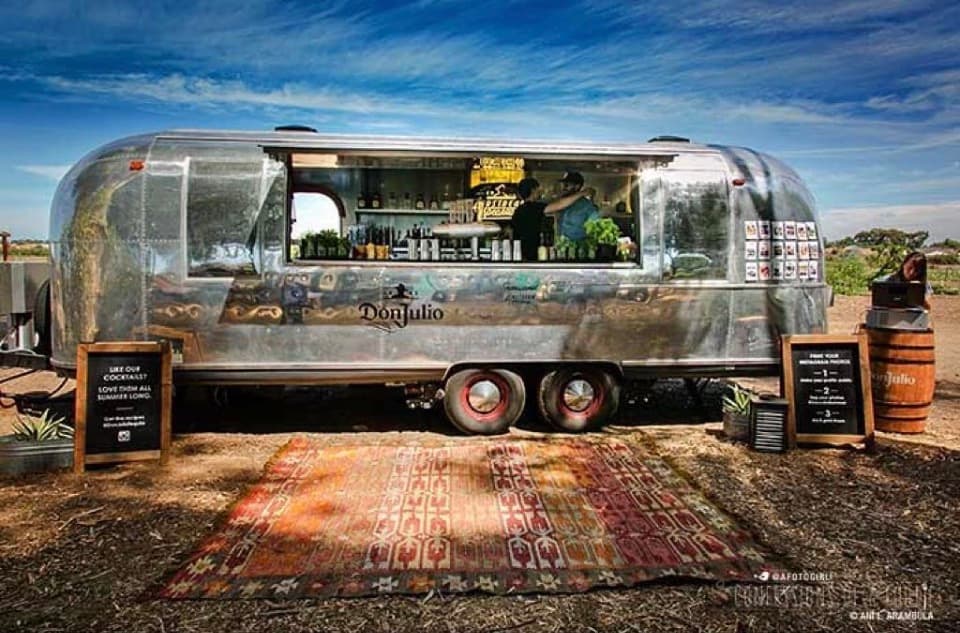 Alcohol brand activation, the Airstream styled with timber barrels, Persian rug and warm lighting