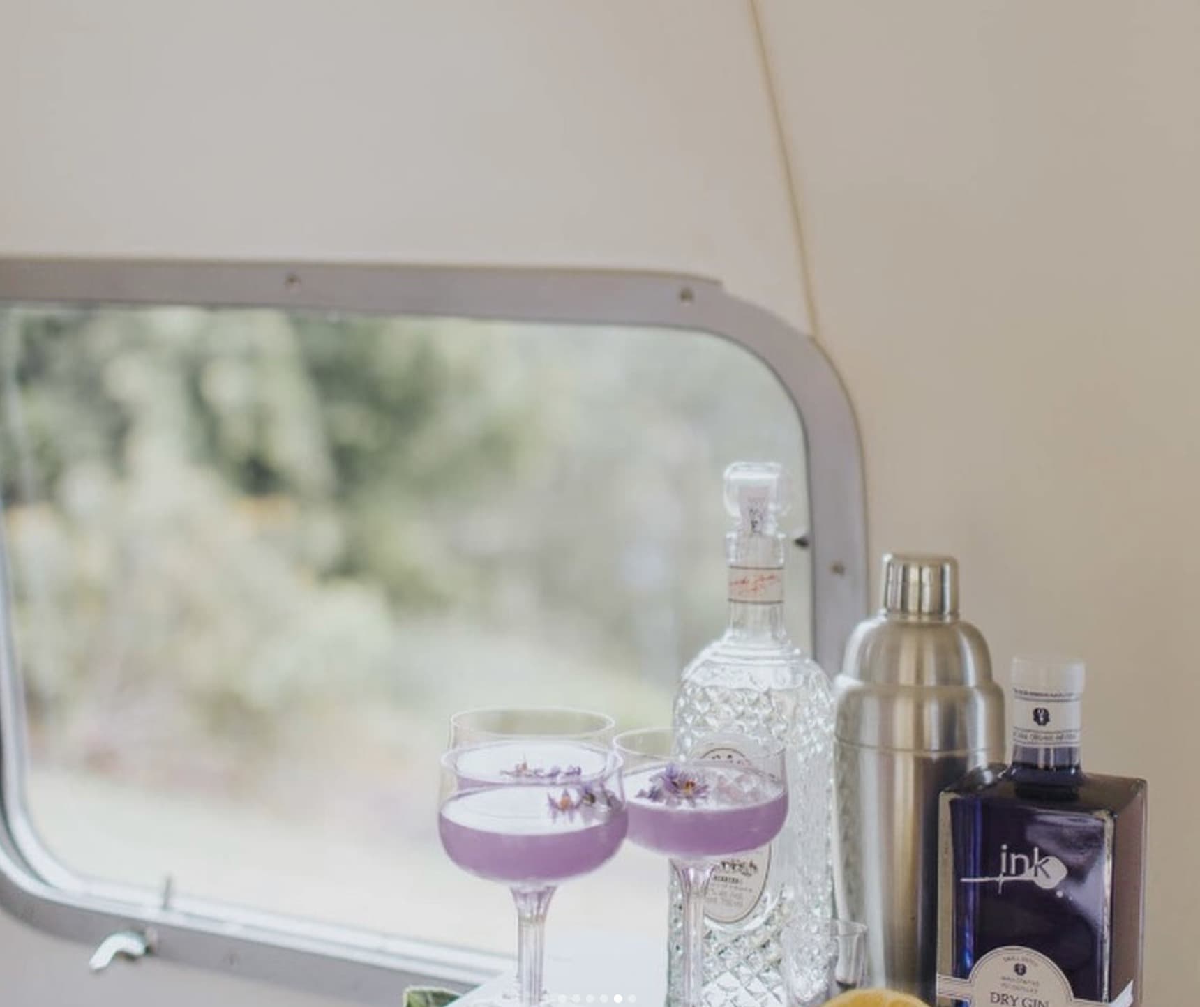 Close up of Ink Gin lavender cocktails by the Airstream window with Ink Gin bottle and shaker