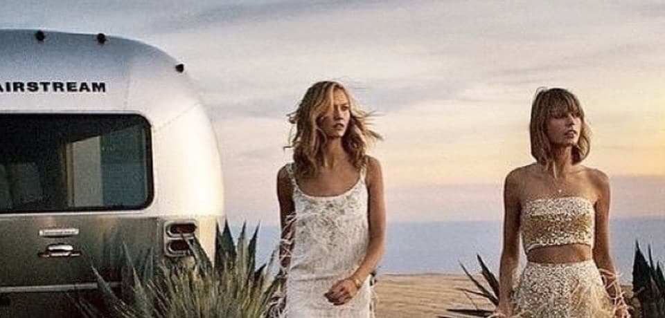 Two models in couture gowns beside the 1972 Airstream at dusk, agave plants and ocean horizon