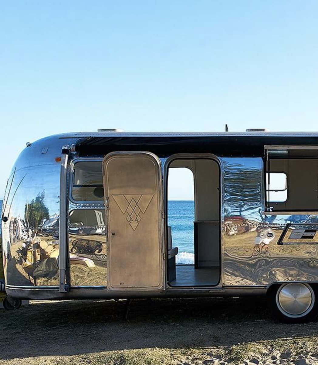 The polished 1972 Airstream, door open, beach behind
