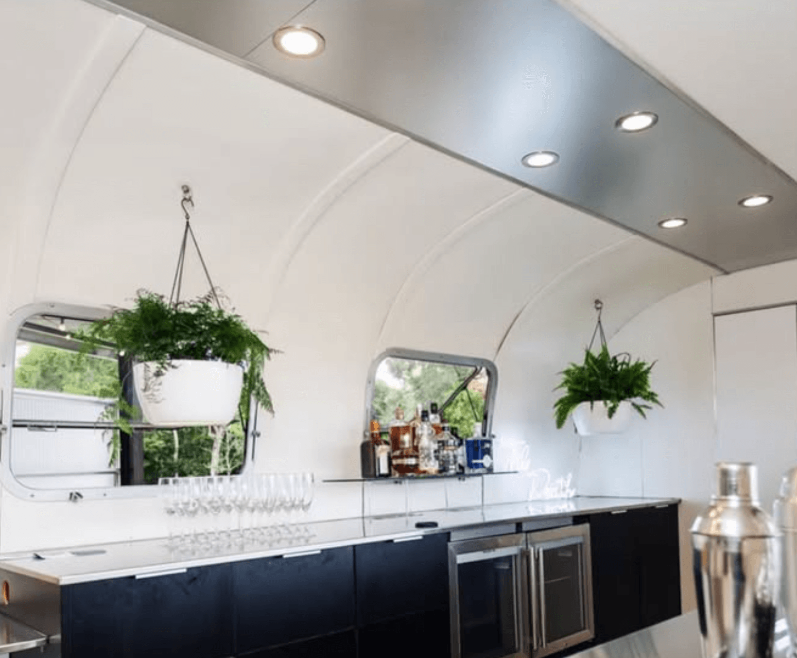 Polished bar interior of the Airstream with glassware and hanging plants