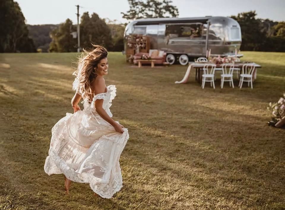 Bride at golden hour with the styled Airstream and reception table behind