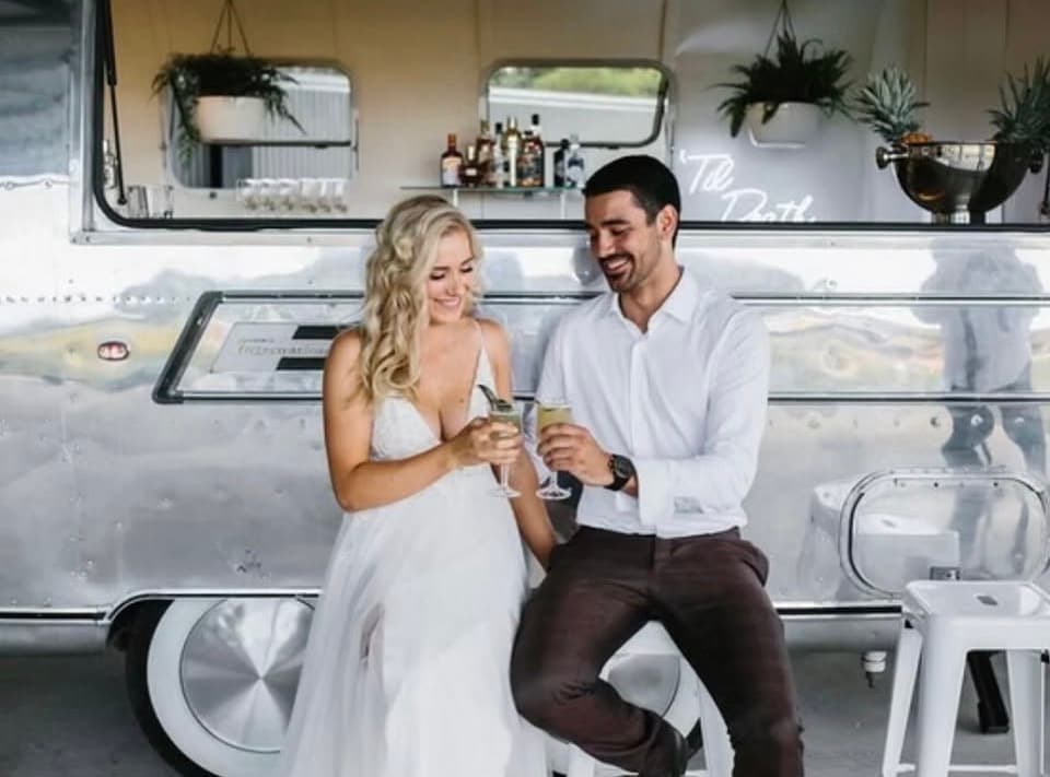Bride and groom toasting champagne at the Til Death bar window